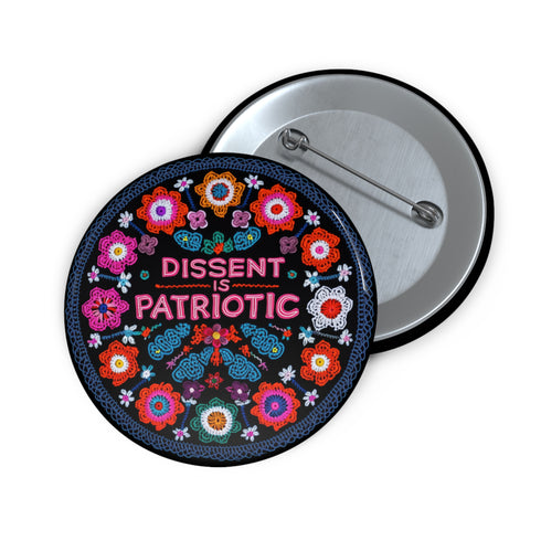 Round black pinback button with vibrant floral embroidery design surrounding bold pink and red text reading "Dissent is Patriotic."